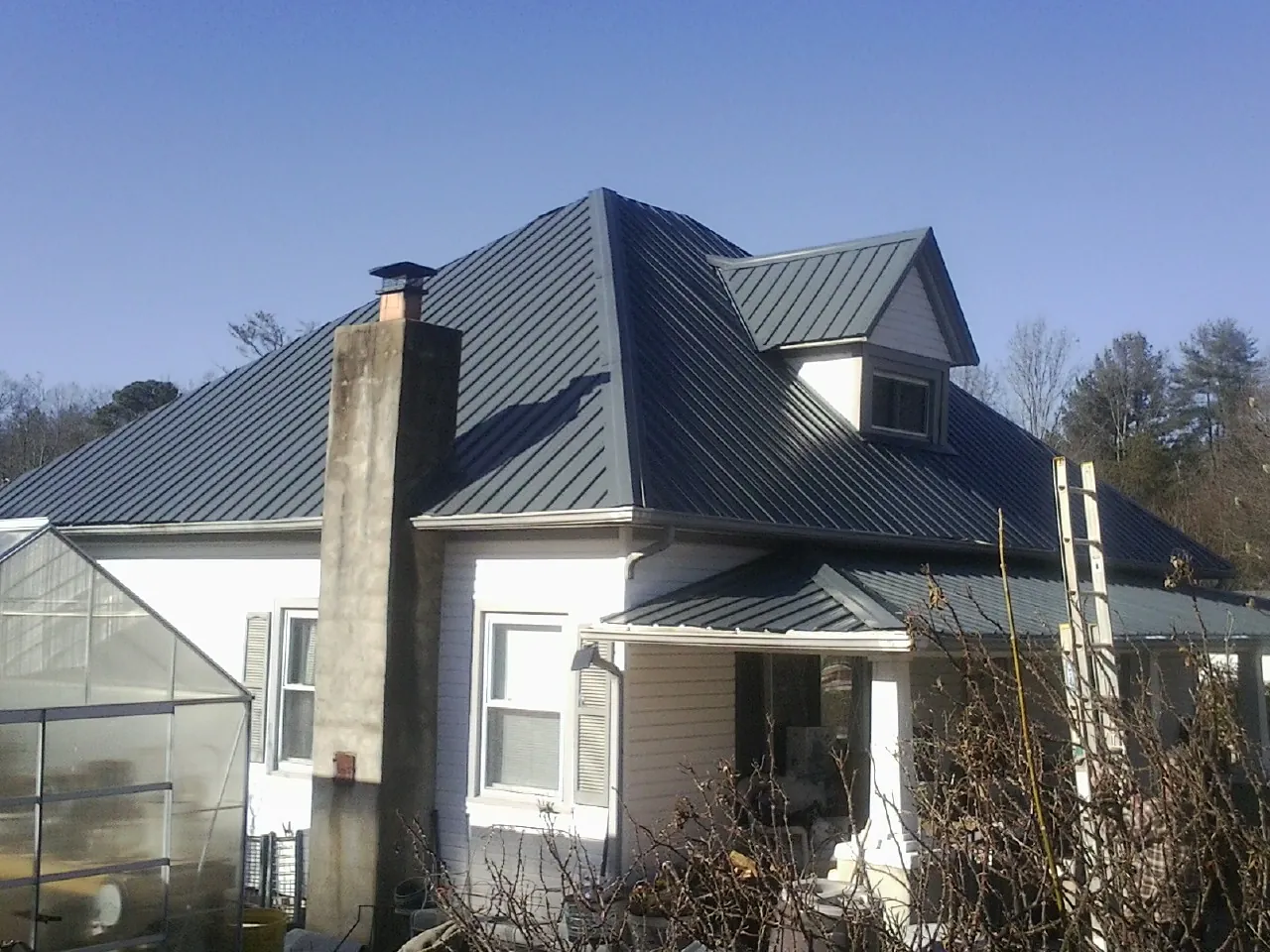 Dark blue standing seam metal roof on a white farmhouse with dormer — Slate & Tile Roof Repair by Roofing Brothers in Poquoson