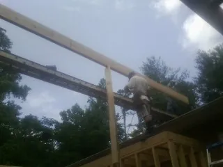 Carpenter setting a ridge beam over a new addition frame — Ice Dam Removal by Roofing Brothers in Poquoson
