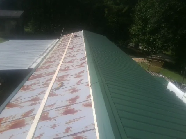 Old rusted panels beside newly installed green metal roofing — Wind Damage Roof Repair by Roofing Brothers in Poquoson