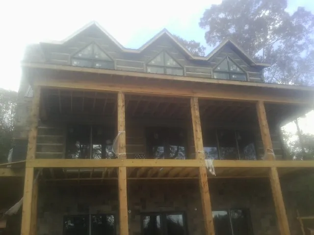 Dormers and porch framing on a large log home under construction — Roof Coating work by our crew in Poquoson