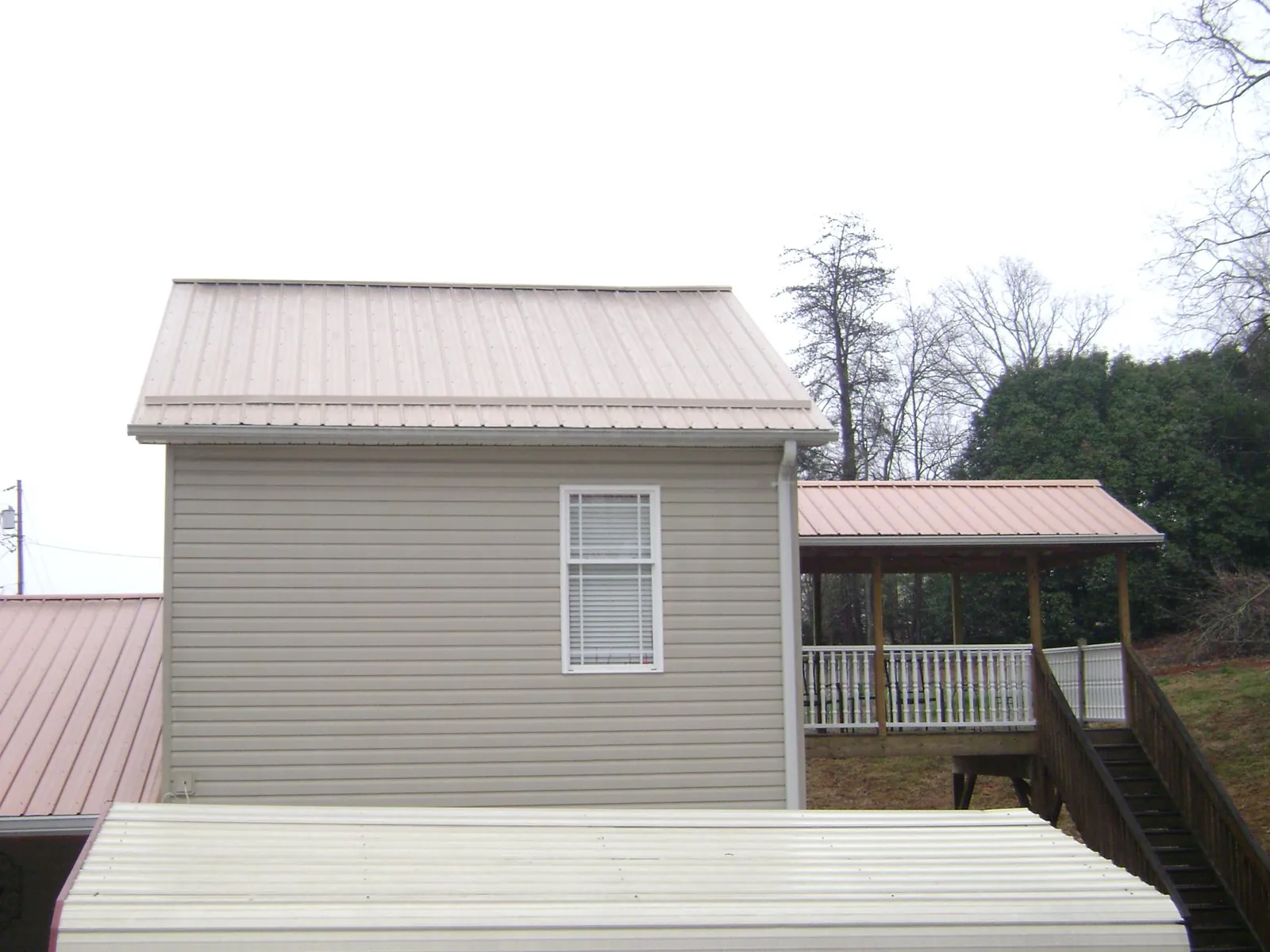 Tan metal roofs on a two story addition and attached porch, from a Roof Replacement job in Poquoson