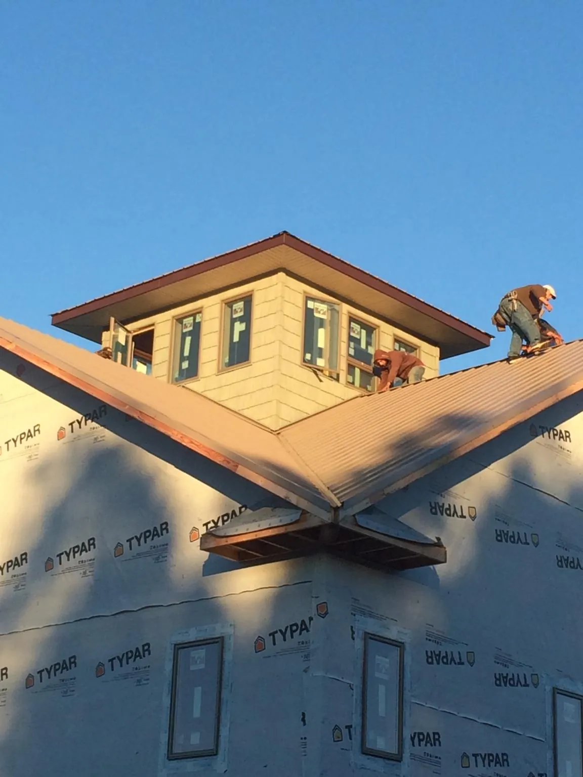 Roofers working around a rooftop cupola on a new metal roof at sunset — Roof Waterproofing in Poquoson by Roofing Brothers